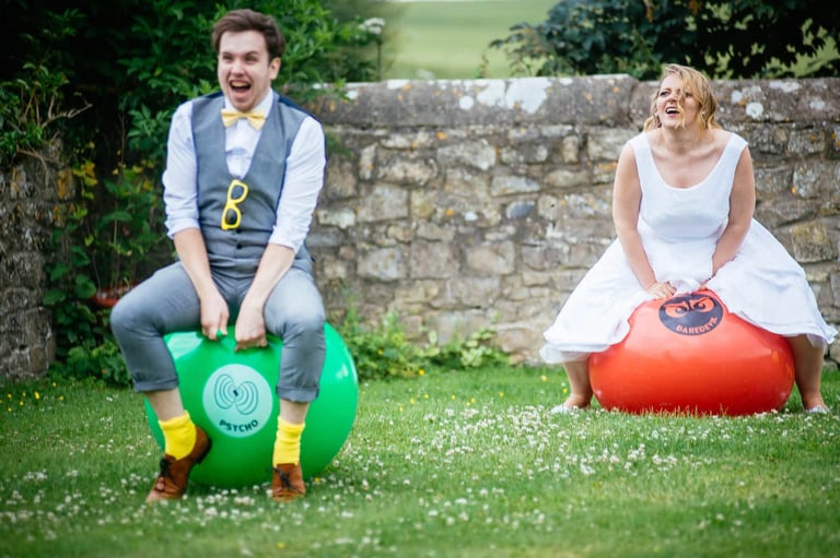 Bride and groom racing on space hoppers at South Wales wedding, captured candidly by photographer Owen Mathias