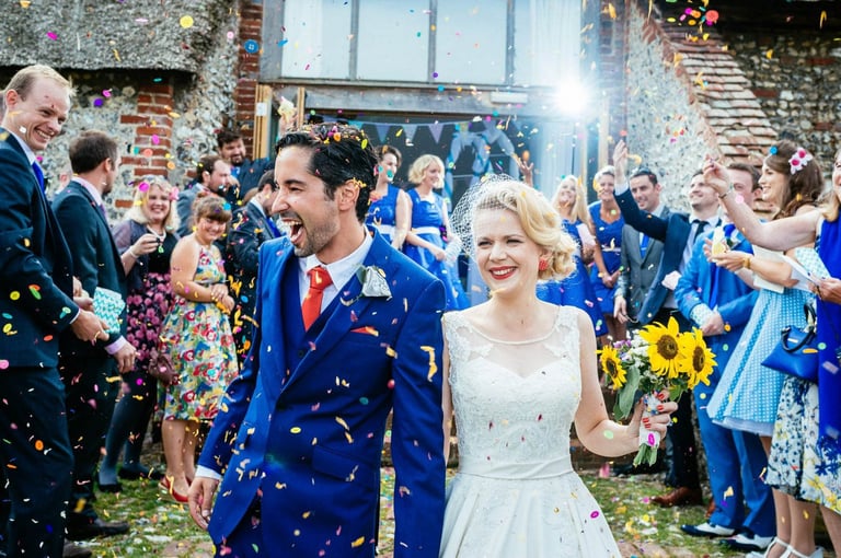 Bride and groom walk through colourful confetti toss at South Wales wedding, captured candidly by photographer Owen Mathias