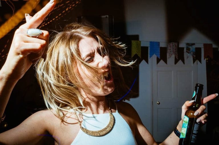 South Wales wedding guest dancing with a beer in hand, hair flying and full of energy on the party dance floor.
