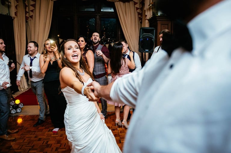 Bride dancing with guests during lively South Wales wedding reception, captured in candid documentary style by Owen Mathias