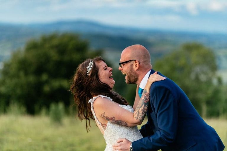 Bride and groom laughing outdoors at South Wales countryside wedding, captured by photographer Owen Mathias
