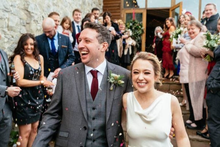 Bride and groom smiling during confetti toss at Rosedew Farm wedding in South Wales by Owen Mathias
