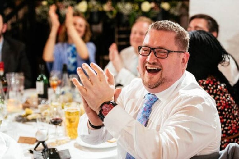 Guest laughing and clapping during wedding speeches at Rosedew Farm in South Wales