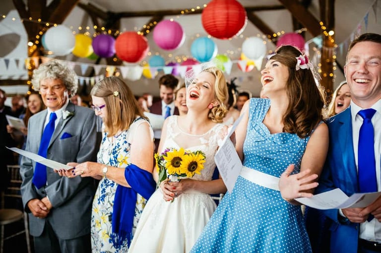 Joyful bride and guests singing during a colourful South Wales wedding ceremony with lanterns and bunting.