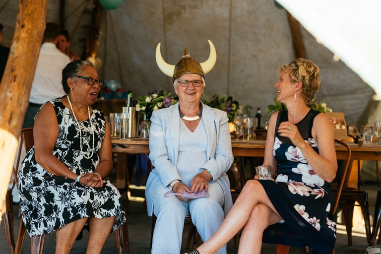 Fun wedding photo at a South Wales tipi wedding with guests laughing, including one wearing a Viking helmet