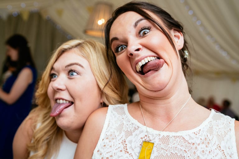 Wedding guests pulling funny faces inside marquee at a South Wales celebration, photographed by Owen Mathias