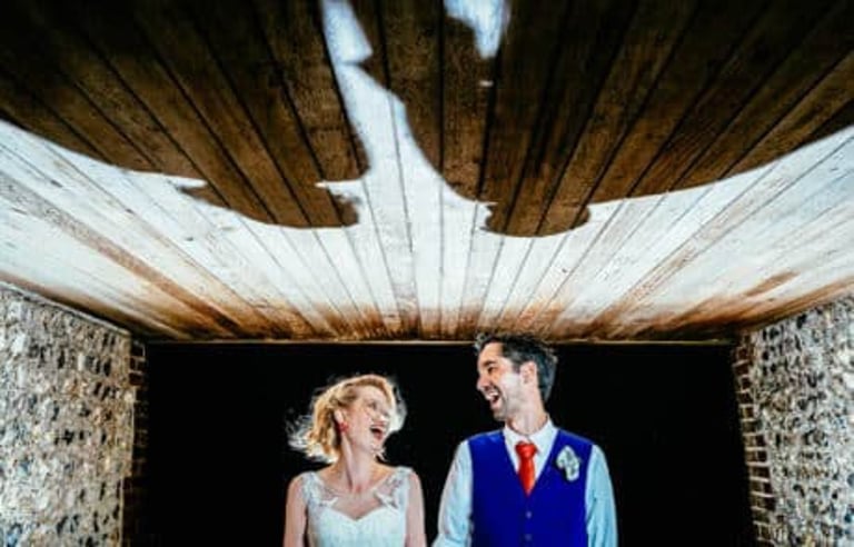 Bride and groom laughing under dramatic shadow at South Wales wedding, captured candidly by Owen Mathias