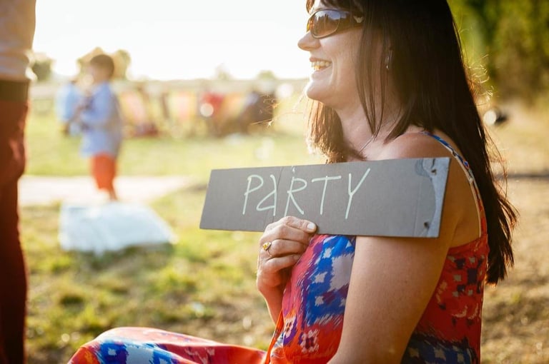 Guest laughing at South Wales wedding holding a sign that reads PARTY during golden hour celebrations