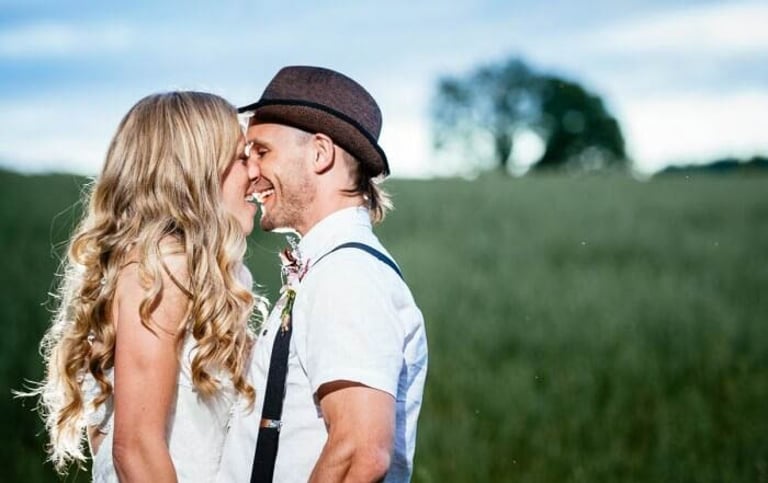 Bride and groom smiling closely in a green field at a South Wales wedding, captured in natural candid style by photographer