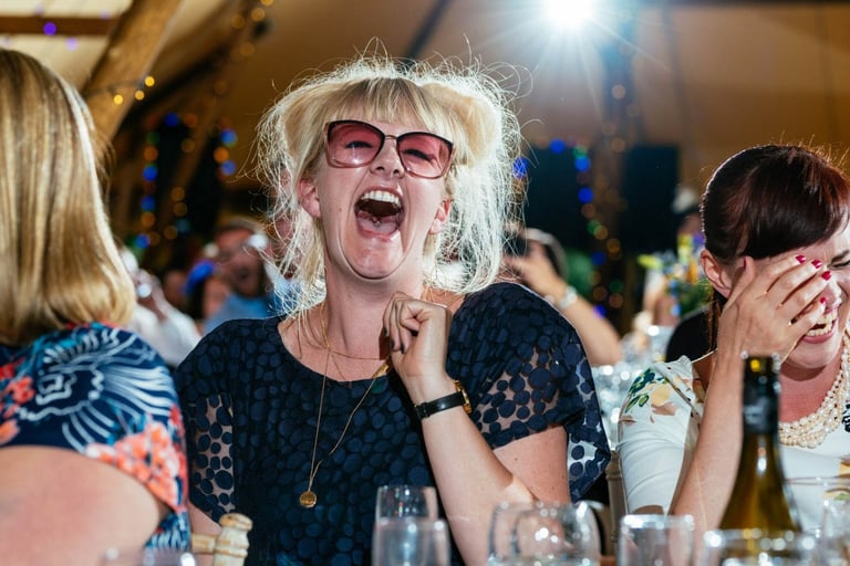 Wedding guest laughs in pink sunglasses during South Wales wedding reception, captured candidly by photographer Owen Mathias