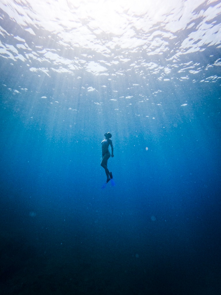 Silhouette of a woman ascending to the surface - freediving
