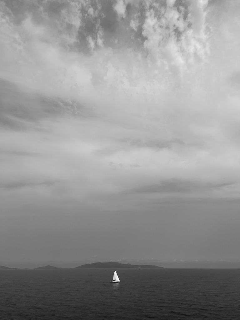 Minimalist black-and-white photo of a sailboat on the sea