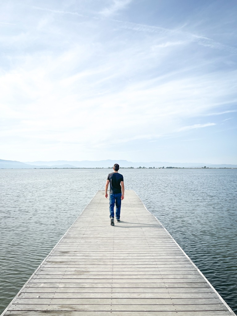Boy walking along a pier, seen from behind
