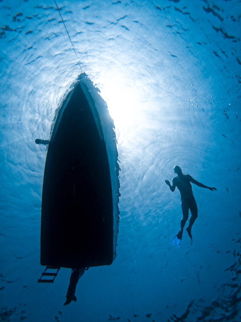 Silhouette of a man and a boat on the sea surface