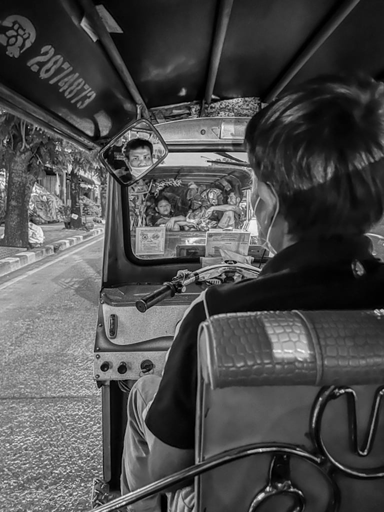 Tuk-tuk driver looking through the rearview mirror