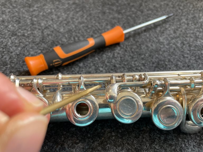 gros plan sur une main tenant un outils pour entretenir une flûte traversière