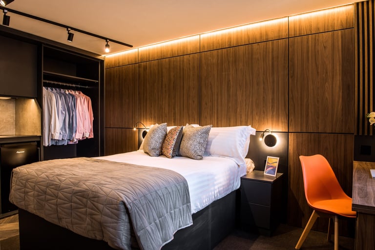 A wide view showing the bed, wardrobe and desk area