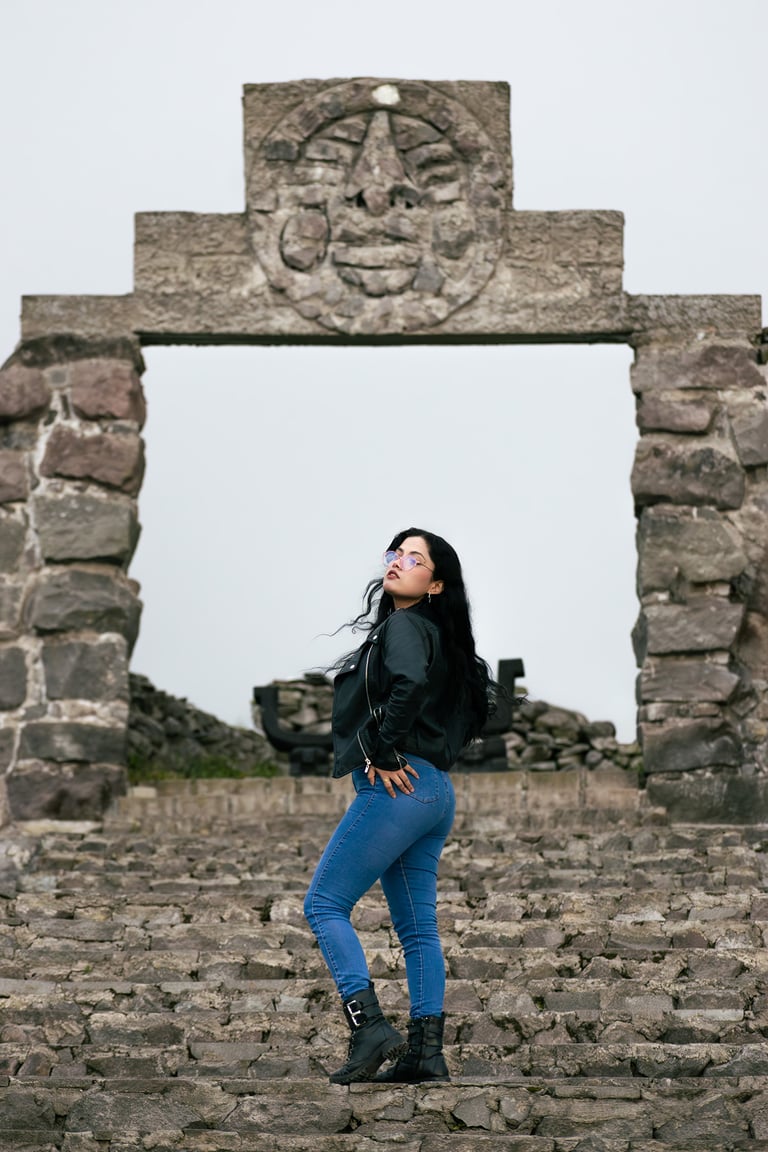 Mujer hermosa posando sensualmente en un graderío de ruinas indígenas con chaqueta de cuero