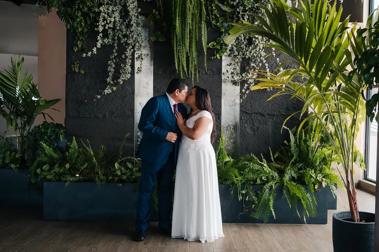 Retrato elegante de novios recién casados dándose un beso en entorno estético de plantas en Quito