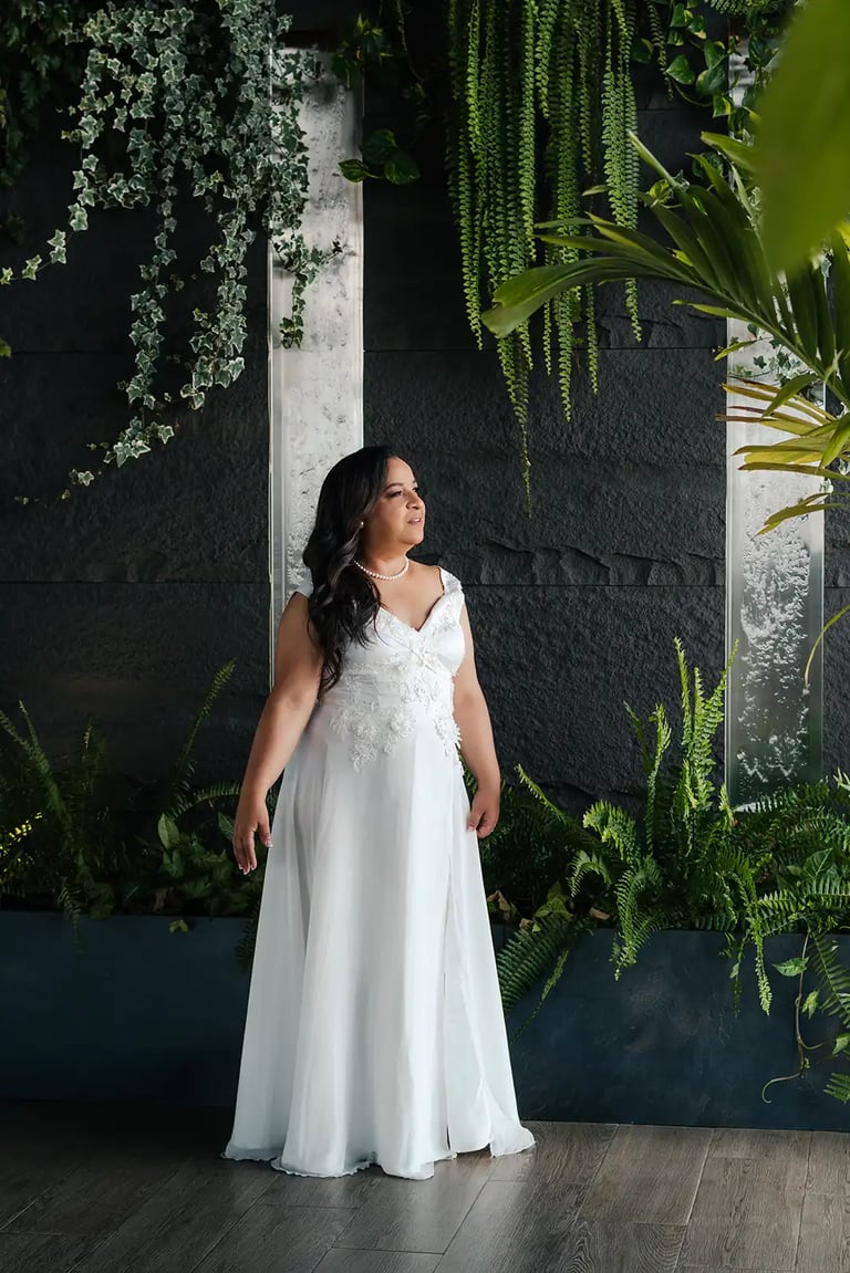 Retrato editorial de novia en su boda premium con su vestido blanco posando elegante rodeada de plantas en Quito