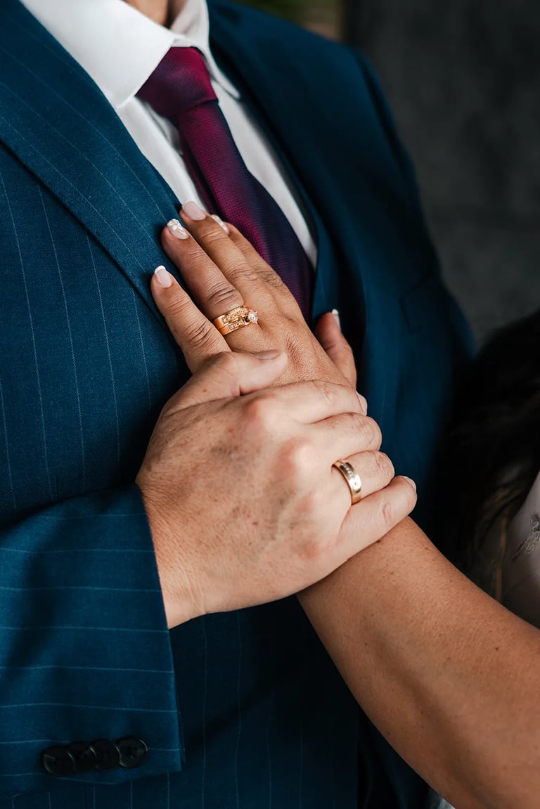 Detalle de anillos en manos de novios en Quito. Fotografía documental de bodas premium.