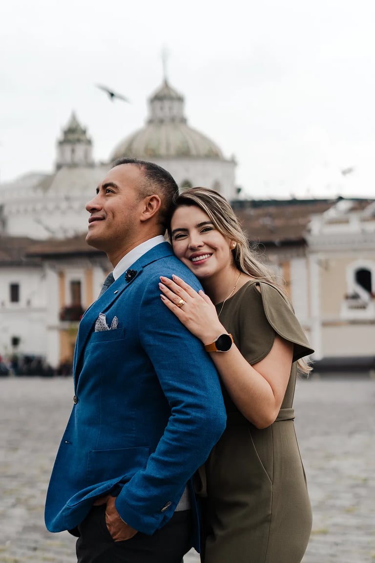 Fotografía de bodas en Quito, Ecuador, pareja de recién casados dándose abrazo plaza de San Francisco sonriendo a cámara