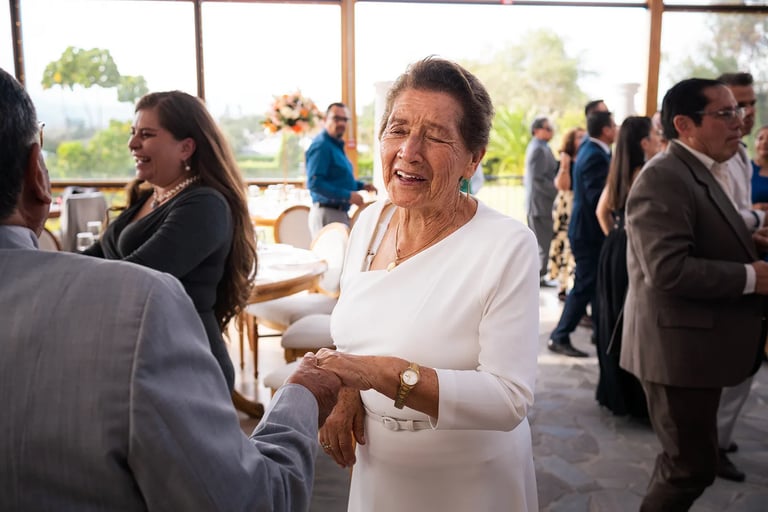 Mujer de la tercera edad con un vestido blanco bailando con su esposo en su boda de oro en Quito, Ecuador
