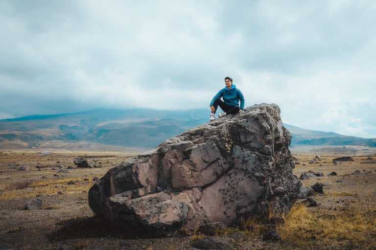Fotografía de retrato profesional de aventura de un joven sentado en la cima de una roca en un paisaje hermoso de montaña