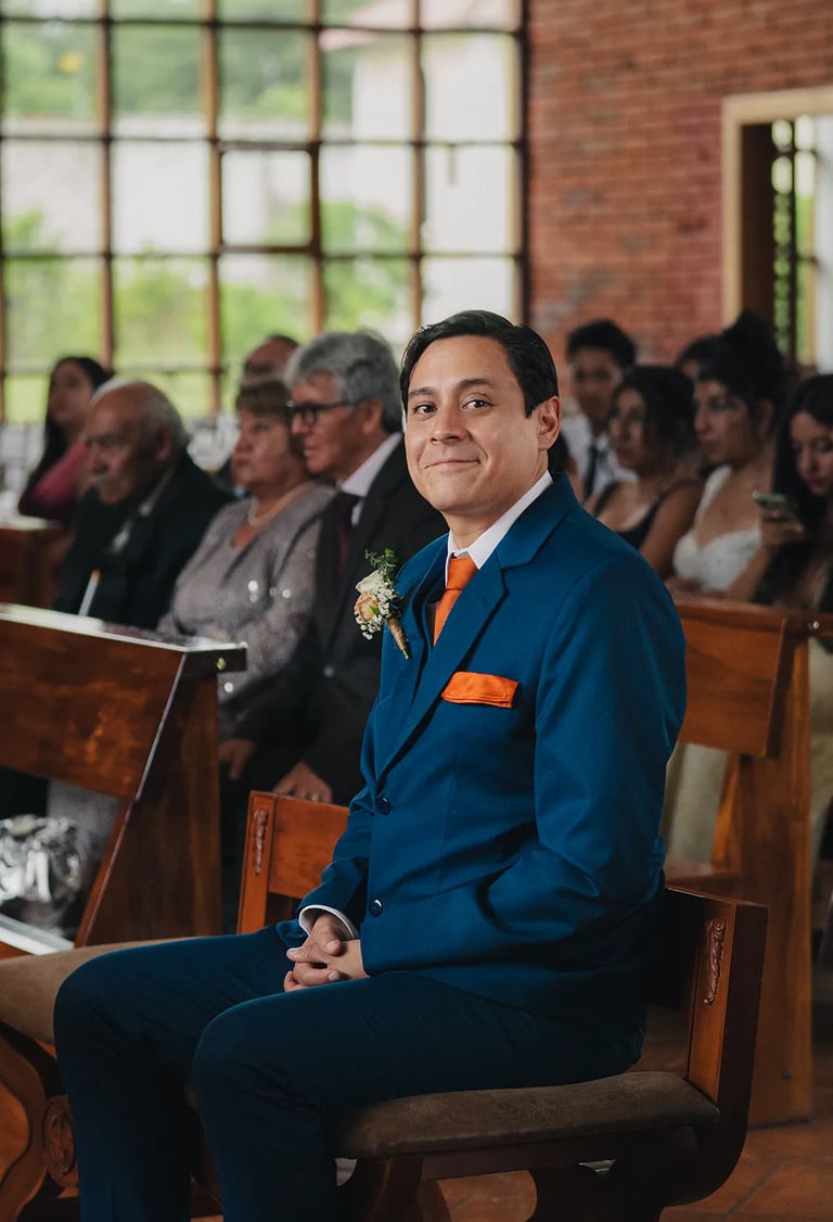 Novio feliz con terno azul sentado esperando en su boda en Quito