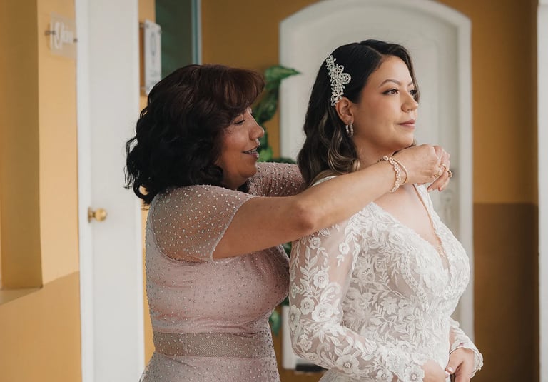 Madre colocandole un collar a su hija con vestido de novia
