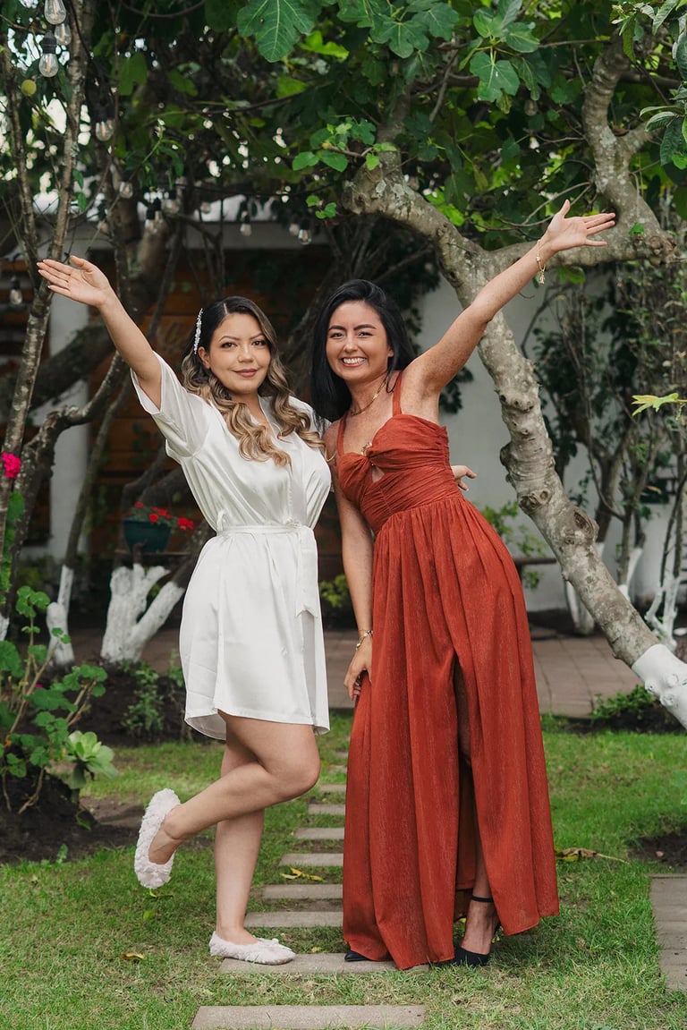 Novia y su dama de honor festejando en un jardín verde