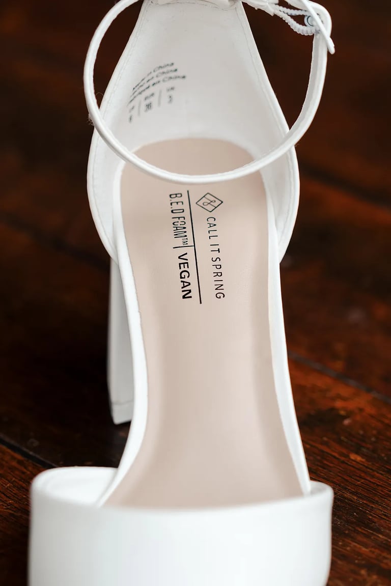 Detalle de zapatilla de novia en el día de su boda sobre fondo de madera