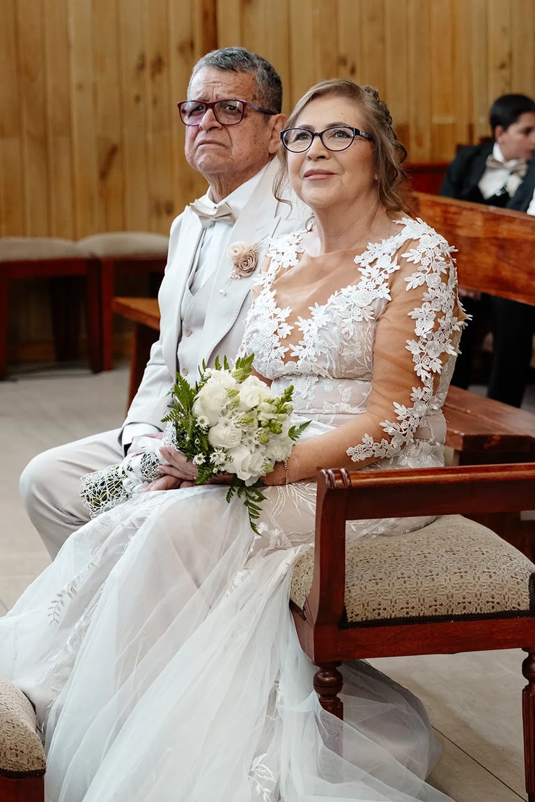 Retrato de bodas de esposos en el altar dirigiendo la mirada hacia el padre oficiante en Quito