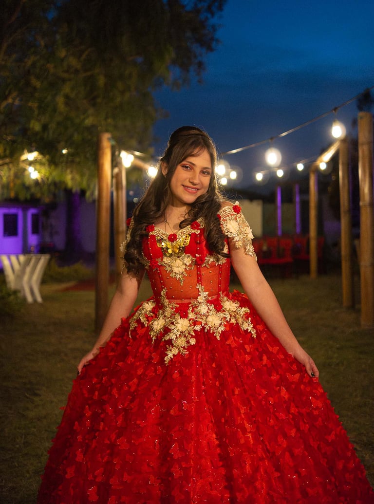 Foto profesional de quinceañera con vestido rojo en la noche con luces naranjas