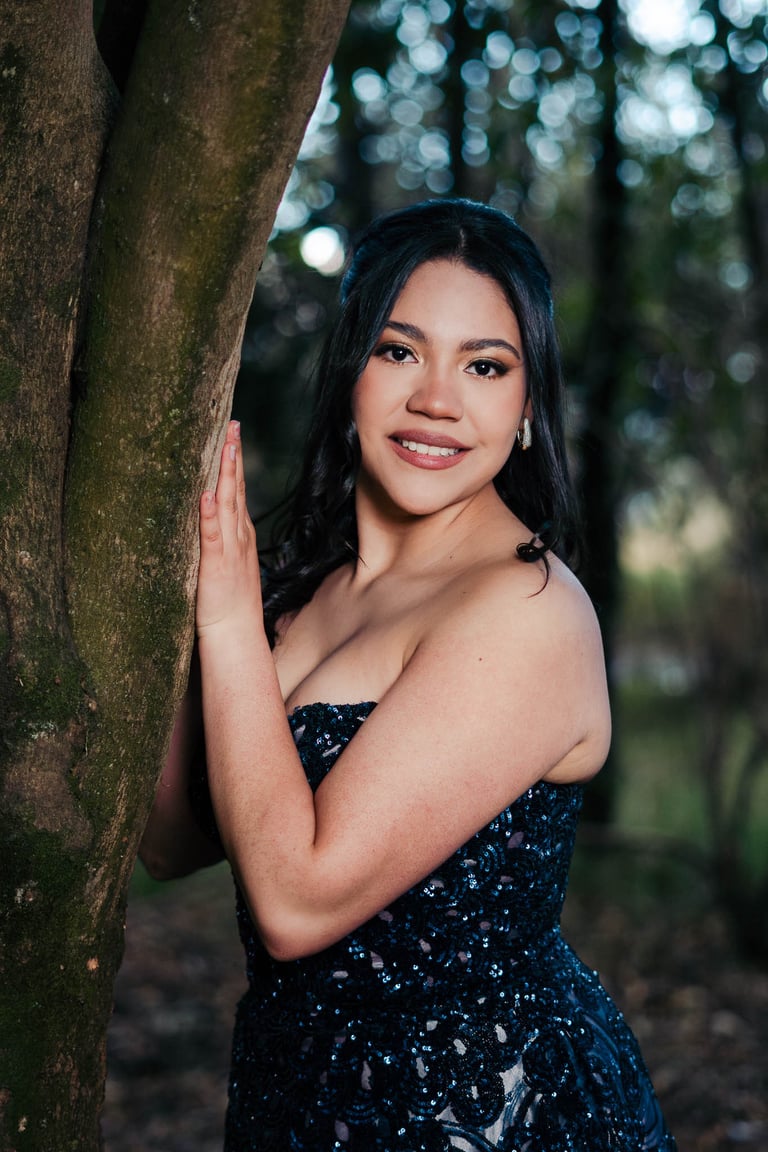 Hermoso retrato profesional de quinceañera con vestido azul elegante en Itchimbía Quito con naturaleza en un árbol