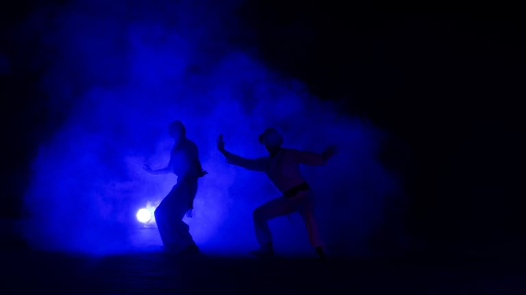 Foto cinematográfica de dos hombres saliendo de un humo azul como siluetas