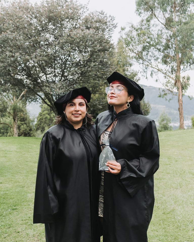 Dos mujeres felices después de graduarse en la universdad en un campo de césped