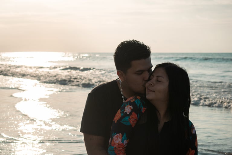 Pareja de novios amorosos dándose un beso con el atardecer en el mar