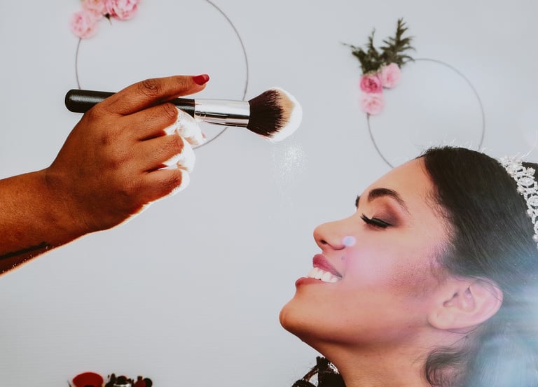Préparation de la mariée avant le mariage, souriante pendant qu'un maquilleur applique délicatement de la poudre sur son visa