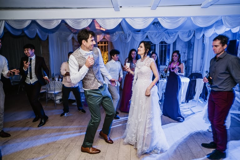 Photo de la fête de mariage : le marié et la mariée dansent entourés d'invités dans une salle de réception décorée, ambiance 