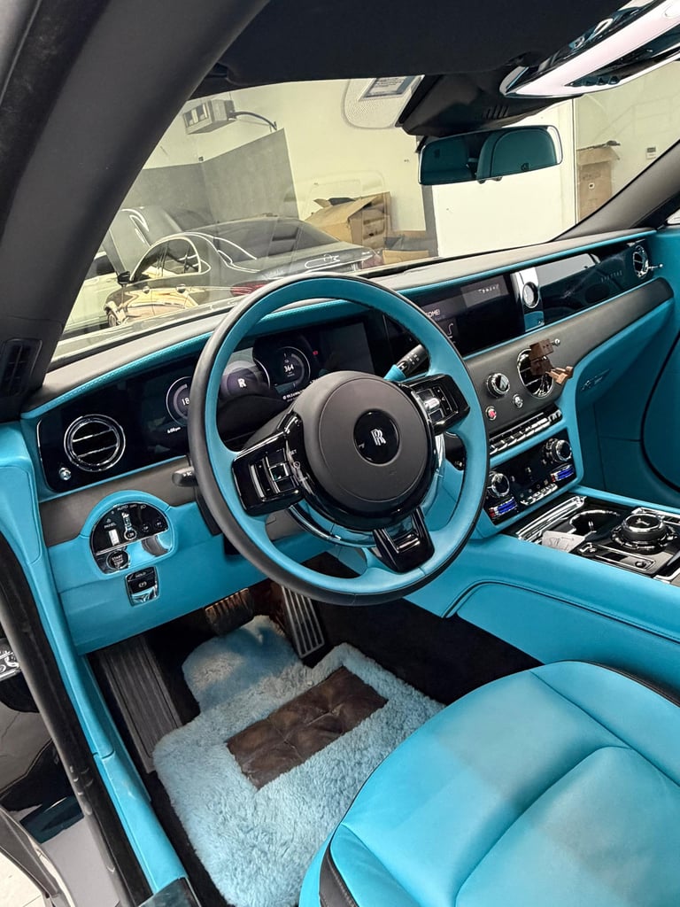 Luxury interior of a Rolls-Royce Spectre featuring a vibrant turquoise leather dashboard and steering wheel.