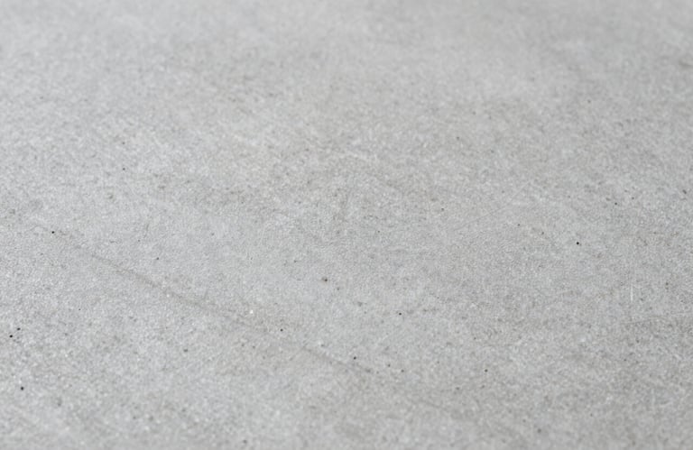 Macro shot of stone-patterned concrete texture, showcasing the fine details and the play of light on the #AEB9B4 surface.