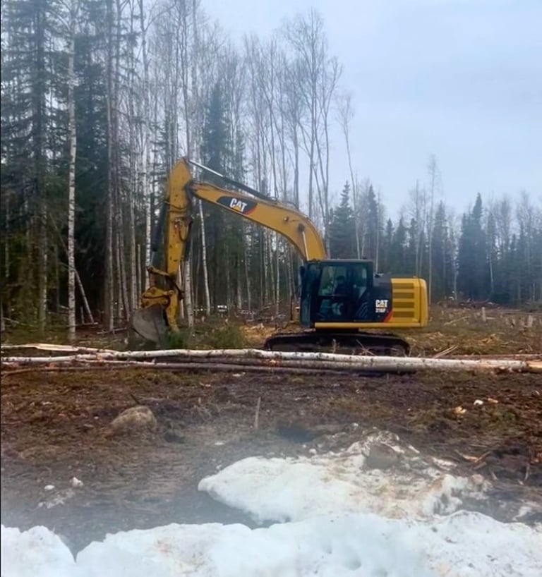 Yellow Cat 316f excavator clearing wooded lot for development in Houston Alaska.