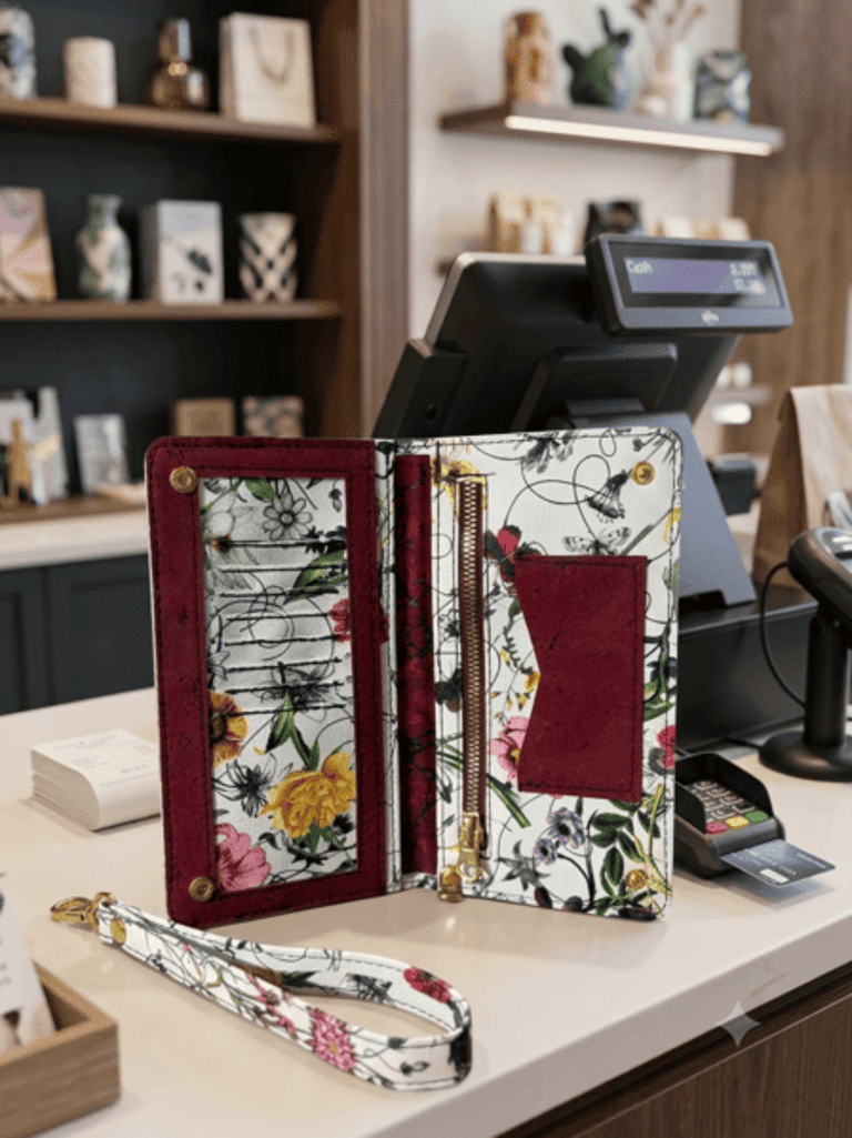 Floral printed leather wallet organizer with wristlet strap on a retail boutique counter.