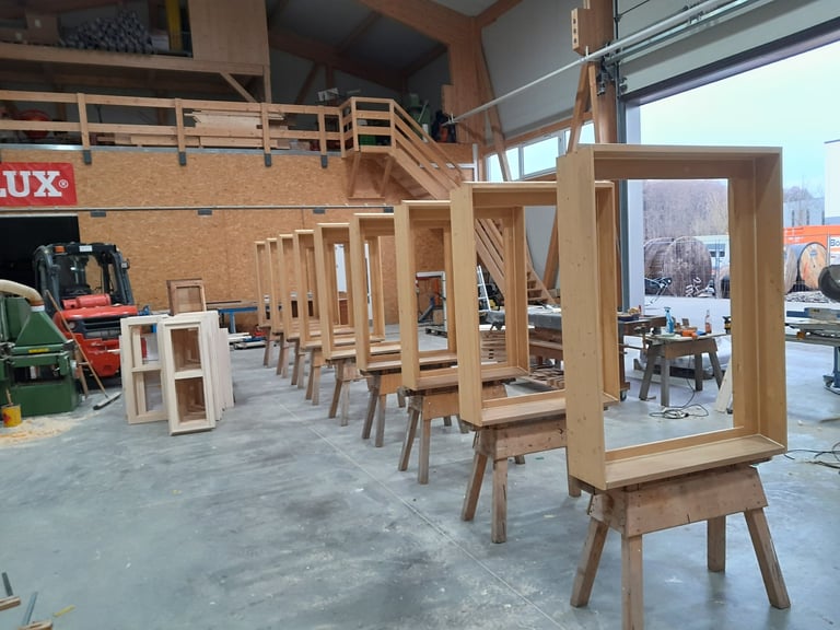 Mehrere maßgefertigte Holzfensterrahmen in der Werkstatt auf Böcken aufgereiht