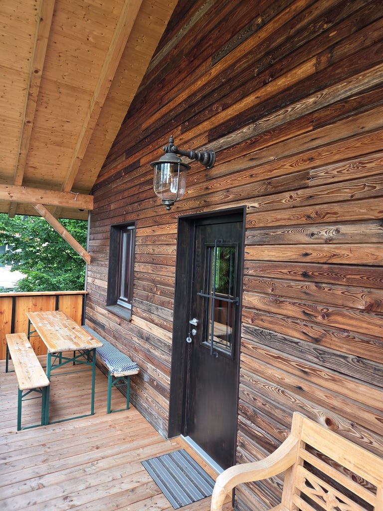 Rustikale Holzfassade mit Balkon und Sitzbereich im Außenbereich von Holztechnik Volk am Ammersee