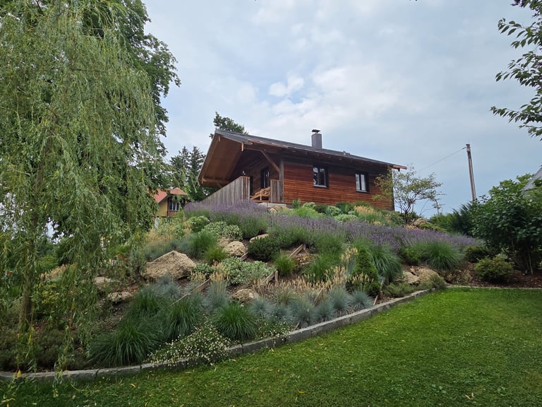 Freistehendes Holzhaus in Hanglage mit Holzfassade und Balkon von Holztechnik Volk am Ammersee