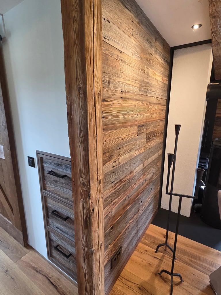 Rustikale Altholz-Wandverkleidung mit massivem Eckbalken, integriertem Schubladenschrank und Eichenparkett.