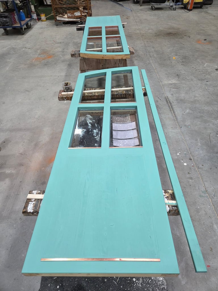 Türblätter in Türkis mit Sprossen-Glaseinsätzen und Kupfer-Details in der Schreinerei-Werkstatt.