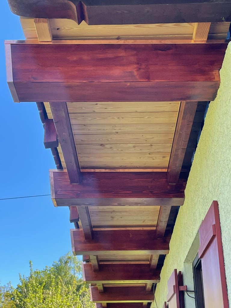 Detailansicht der massiven Holzbalken-Konstruktion eines bayerischen Balkons mit hochwertiger Lasur.